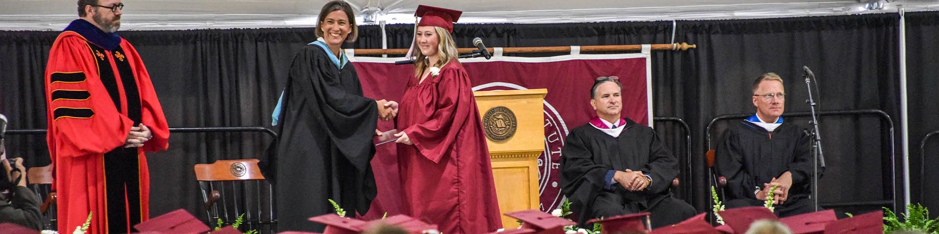Image of a student being given her diploma at LI's Commencement ceremony. 